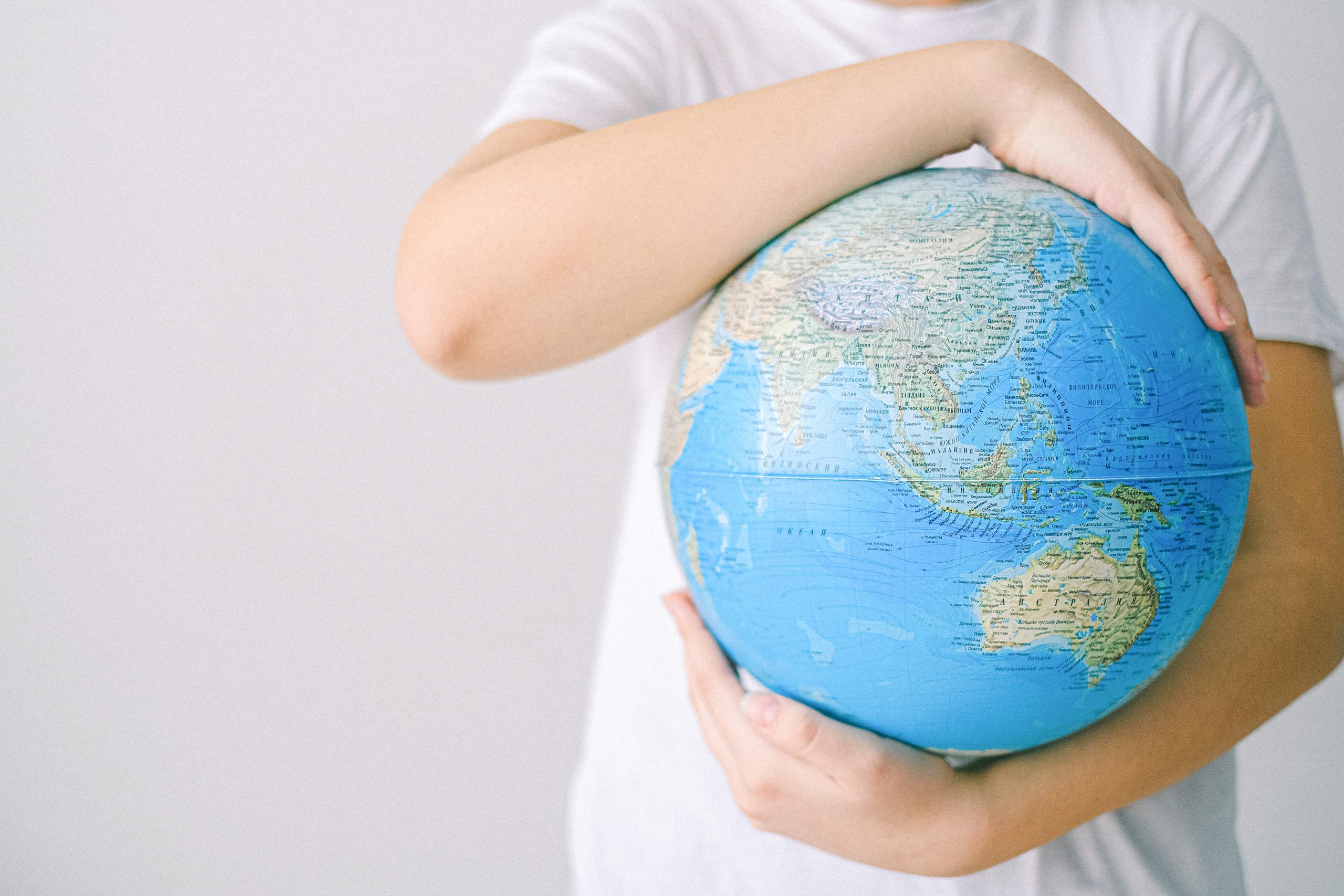 Child holding a globe against a white background, symbolizing global connection and unity.