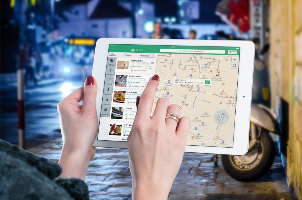 The Tools That Finally Got Me Replies: A Resume Ghosting Survival Plan Hands using a digital map on a tablet in an urban setting at night, illustrating navigation and technology.