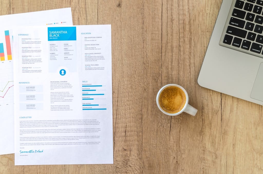 The Tools That Finally Got Me Replies: A Resume Ghosting Survival Plan Top view of a desk with resume, coffee cup, and laptop on a wooden surface, ideal for business concepts.