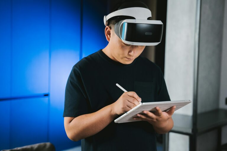 Top AI Tools Every Remote Worker Should Learn in 2025 A man indoors wearing a VR headset while writing on a tablet with a stylus pen.