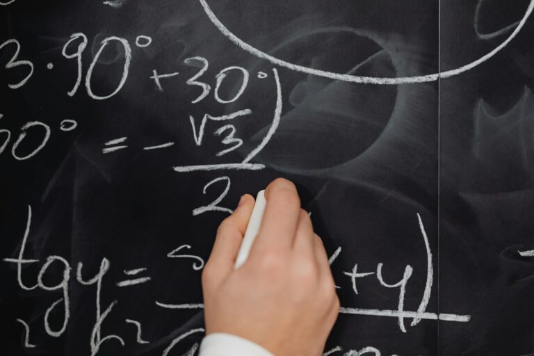 A hand vividly writing complex mathematical equations on a chalkboard.