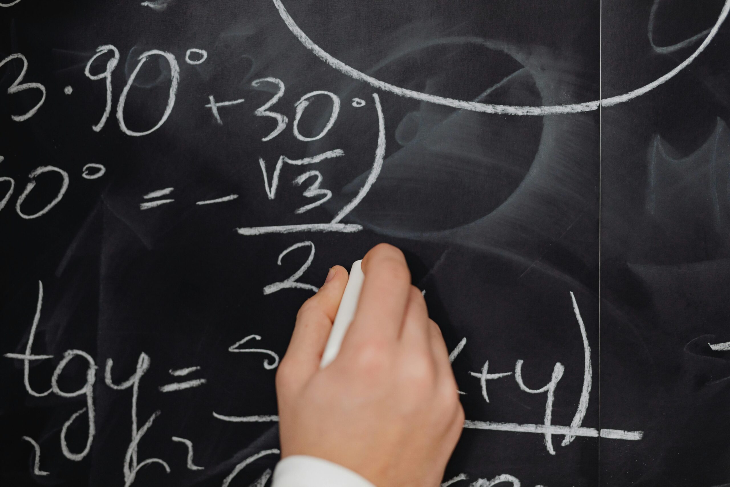 A hand vividly writing complex mathematical equations on a chalkboard.