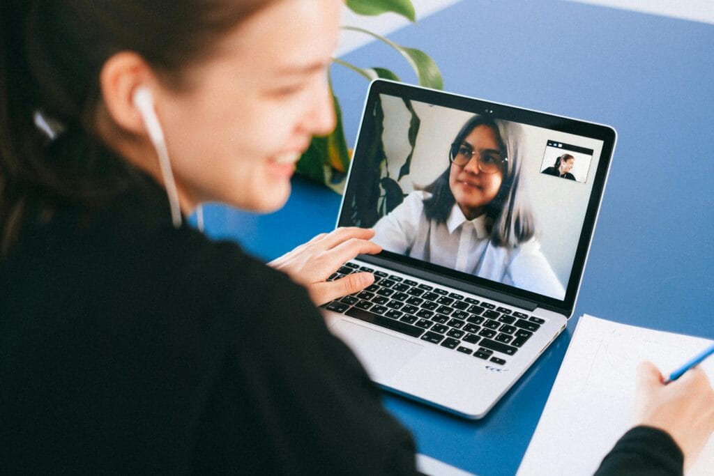 pexels-photo-4226262-4226262 Woman having a video conference on a laptop, smiling and taking notes.